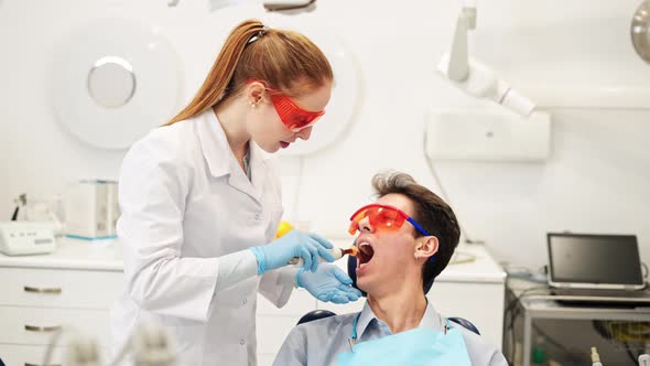 Friendly Female Dentist Talking with Smiling Male Patient Speaking After Composite Dental Filling