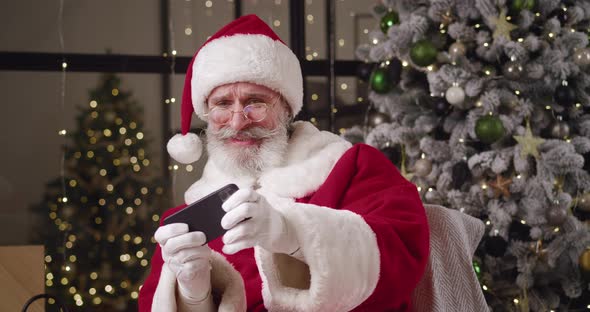 Joyful Elderly Caucasian Man with Gray Beard in Santa Claus Carnival Red and White Costume with Hat