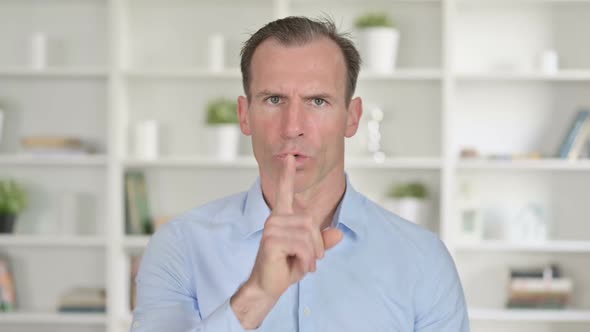 Portrait of Middle Aged Businessman Putting Finger on Lips