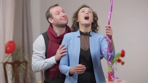 Excited Loving Adult Couple Looking at Balloons Passing at Front Hugging and Kissing