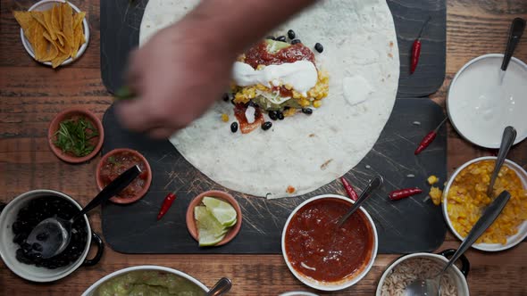 Overhead View of Adding Ingredients To Tortilla and Making a Burrito