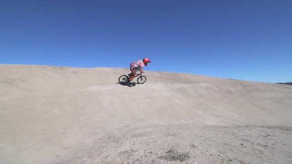 A young woman bmx rider riding bike on a dirt track.