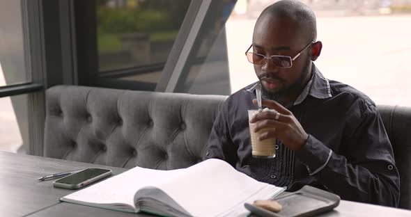 Young Black Businessman Talks on the Phone in a Cafe