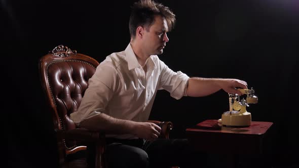 a Man on Black in a White Shirt Sits in a Chair