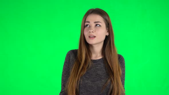 Portrait of Cute Brunette with Long Hair Is Looking Straight and Smiling on a Green Screen