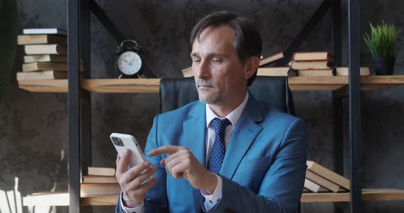 Professional Senior Business Man Holding Modern Smartphone Texting Message in Office