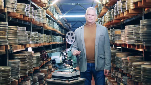 Male Archivist is Standing Next to an Old Movie Projector