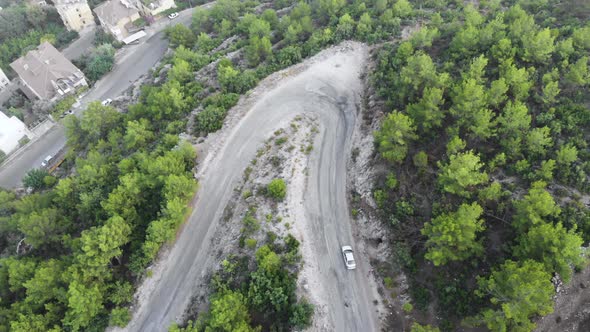 Aerial view of cars driving on curved, zigzag road or street on mountain hill with green natural 