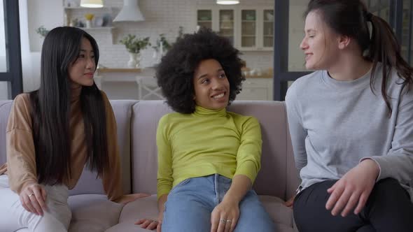Cheerful Young Multinational Women Sitting on Couch Talking