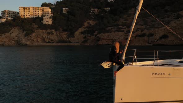 Beautiful Woman on the Bow of the Yacht at Sunset