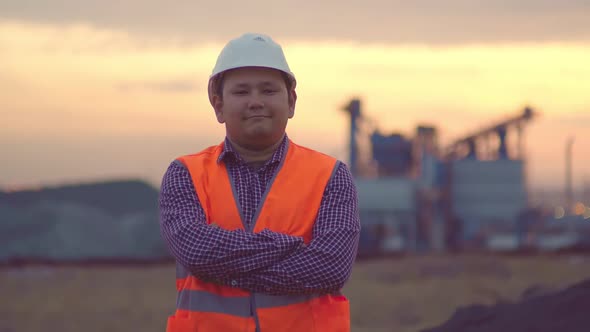 Evening Portrait of a Happy Engineer on the Background of the Plant. Middle-aged Man of Asian