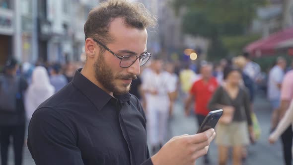 Young man using phone in crowd.