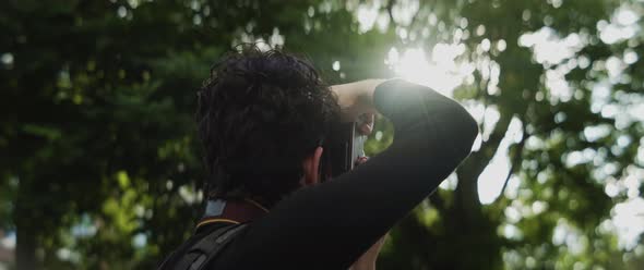 Man taking pictures of the light shining through the trees