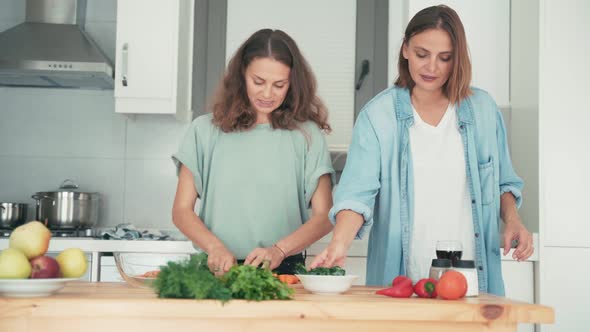 Two Young Pretty Caucasian Women Cooking in the Bright Kitchen.