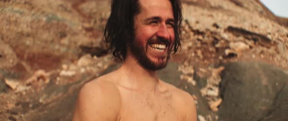 Surfer smiling and talking while is taking off his wetsuit at the beach