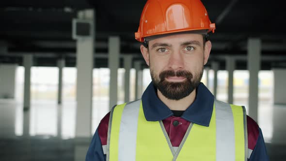 Slow Motion Portrait of Builder in Uniform Looking at Camera and Nodding Head Smiling