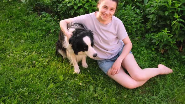 Smiling Young Attractive Woman Stroking Playing with Cute Puppy Dog Border Collie on Summer Outdoor