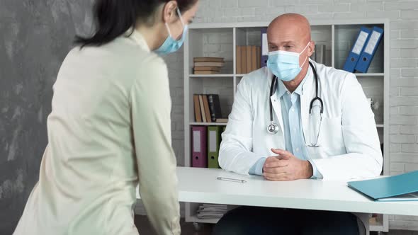 Mature Doctor in Protective Mask Meeting and Giving Handshake To Female Patient During Medical