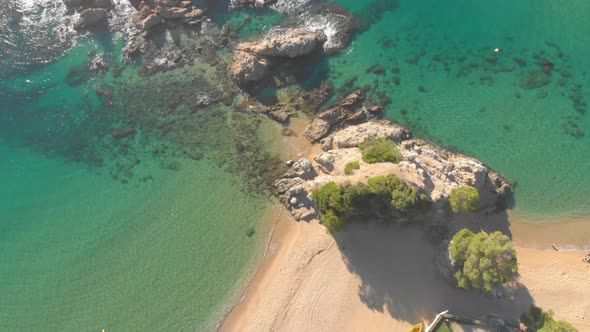 Aerial, top down, birdseye, drone shot, sideways, over rocky coast, turquoise sea and the Lloret de