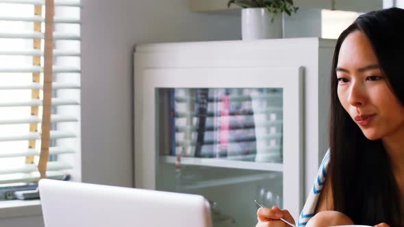 Beautiful woman having cereal while using laptop