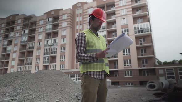 Construction Inspector with Blueprints on Building Site