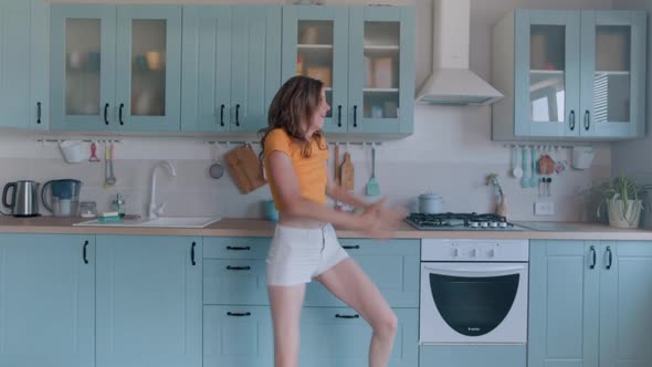 A Beautiful Woman in White Shorts is Relaxing at Home Dancing in the Kitchen