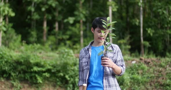 Asian Man Holding Plant And Looking