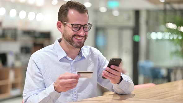 Businessman Making Successful Online Payment on Smartphone in Office 