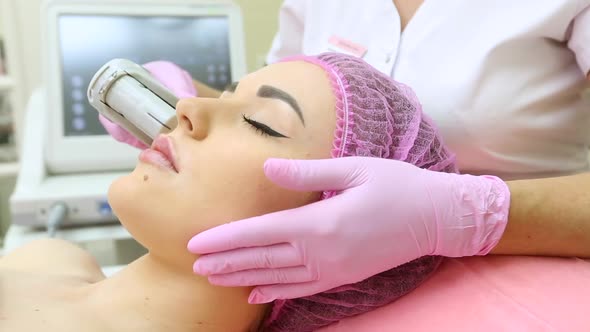 Ultrasonic face lifting of a young beautiful woman. Pulling the skin. Modern cosmetology.