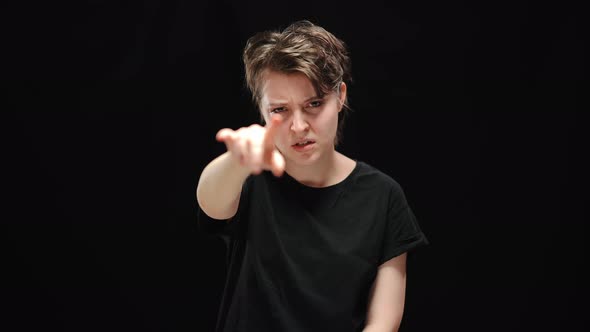 Middle Shot of Brunette Young Woman Pointing at Camera with Angry Facial Expression