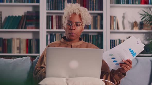 African American Female with Laptop Looking Documents with Financial Report
