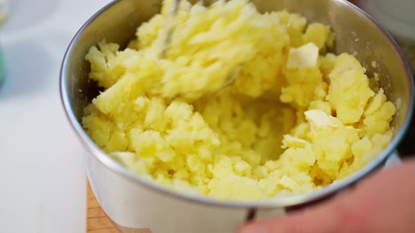 Female Hand Mashes Boiled Potatoes with a Pusher Making Mashed Potatoes