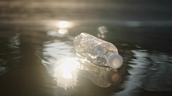 Plastic Bottle Floats in Rippling Water at Sunset Light