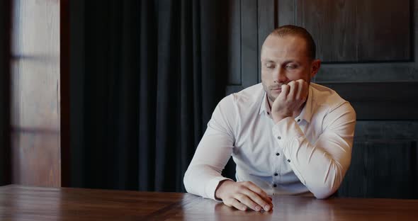 Tired Man Sitting Waiting at a Table Indoors Trying To Keep Himself From Falling Asleep Jerking