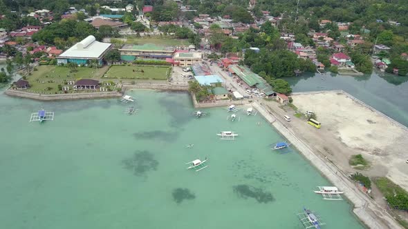 Aerial view circling around above the Moalboal port on Badian Bay with various banca boats in the wa