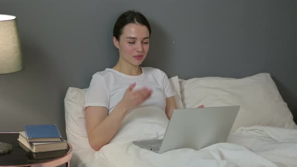 Video Chat on Laptop By Young Woman in Bed 