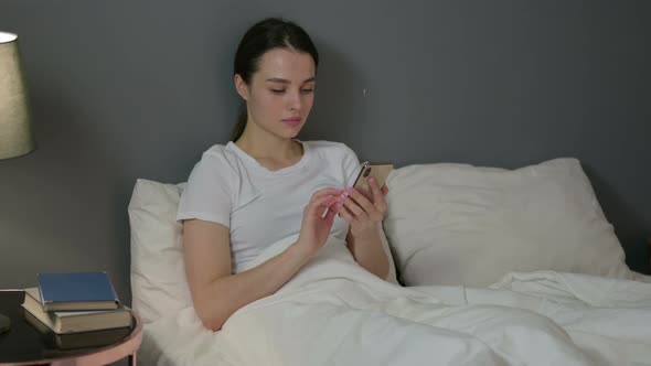 Smartphone Use By Young Woman in Bed 