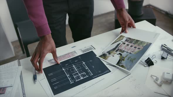 Man is working on the blueprints of a newly developed building. Analyzing images and flipping them o