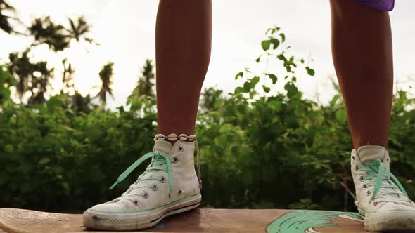 A girl skateboarding peacefully through the scenic palm tree forest.