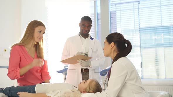 Young Doctor Pediatrician Talking with Child Girl Patient