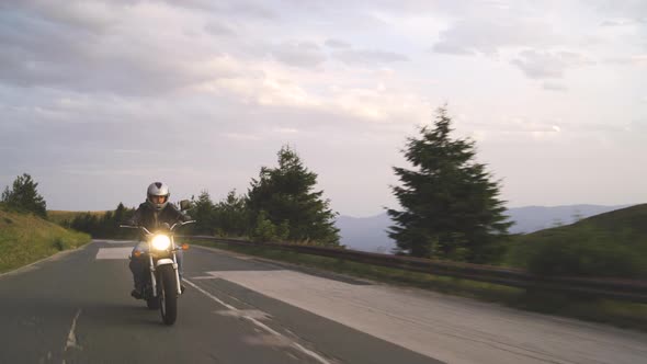 Adventurous Male Biker on Motorcycle Driving on Mountain Asphalt Road