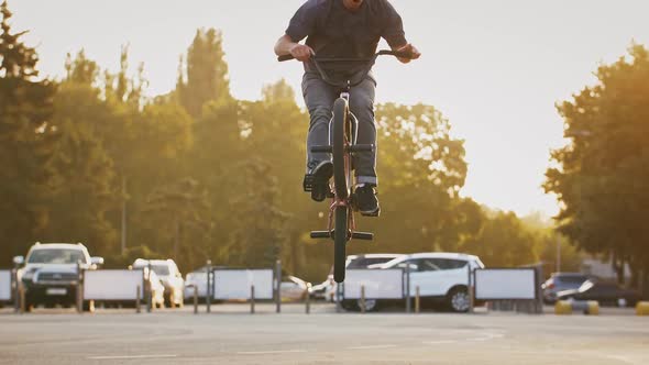 Skillful Guy Bmx Rider is Bouncing and Turning Handlebars of His Bike Doing Tricks While Exercising