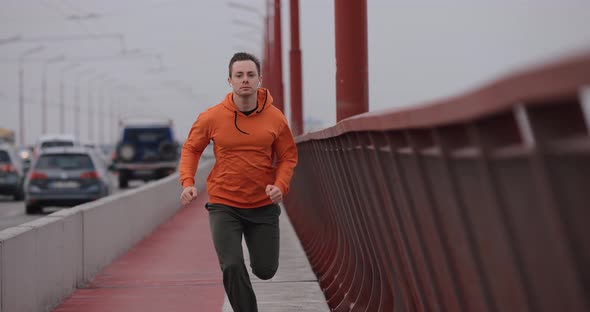 Man in Orange Hoodie Running Fast on a Bridge Slow Motion