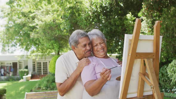 Video of happy biracial senior couple painting in garden