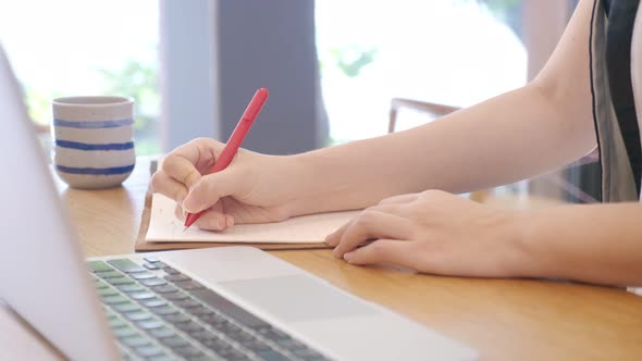 Close up shot of unrecognizable woman working, writing on a notebook,making note