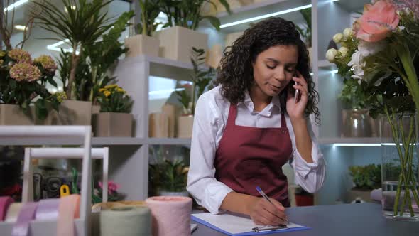 Pretty Florist Working on Cellphone in Flower Shop