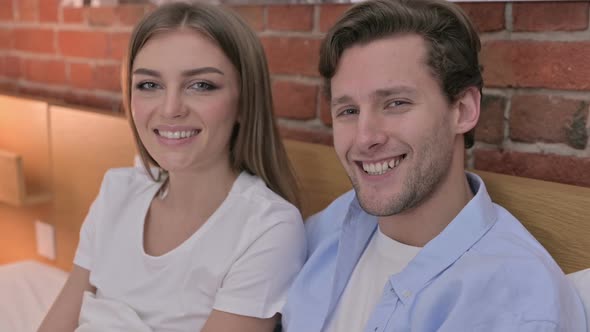 Portrait of Cheerful Young Couple Smiling at Camera From Bed