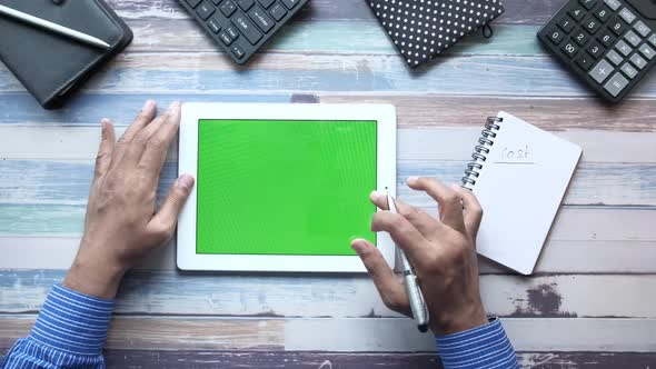 Top View of Businessman Using Digital Tablet and Writing on Notepad 