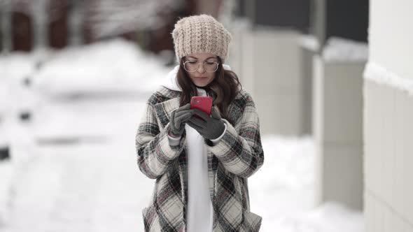 A Young Darkhaired Woman in Round Glasses Is Outside on a Winter Day Standing Looking at Her