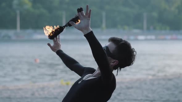 Portrait Skillful Young Slim Man in Black Clothes and Mask Performing a Show with Flame